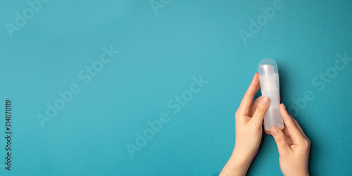 Masturbation concept. Female hands holding a plastic bottle with a lubricant on a blue background with copyspace