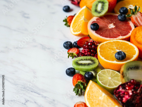 Multicolored seasonal healthy natural fruit composition with persimmon, blueberries, orange, kiwi, strawberries, grapefruit, pomegranate, orange slices. Copy space