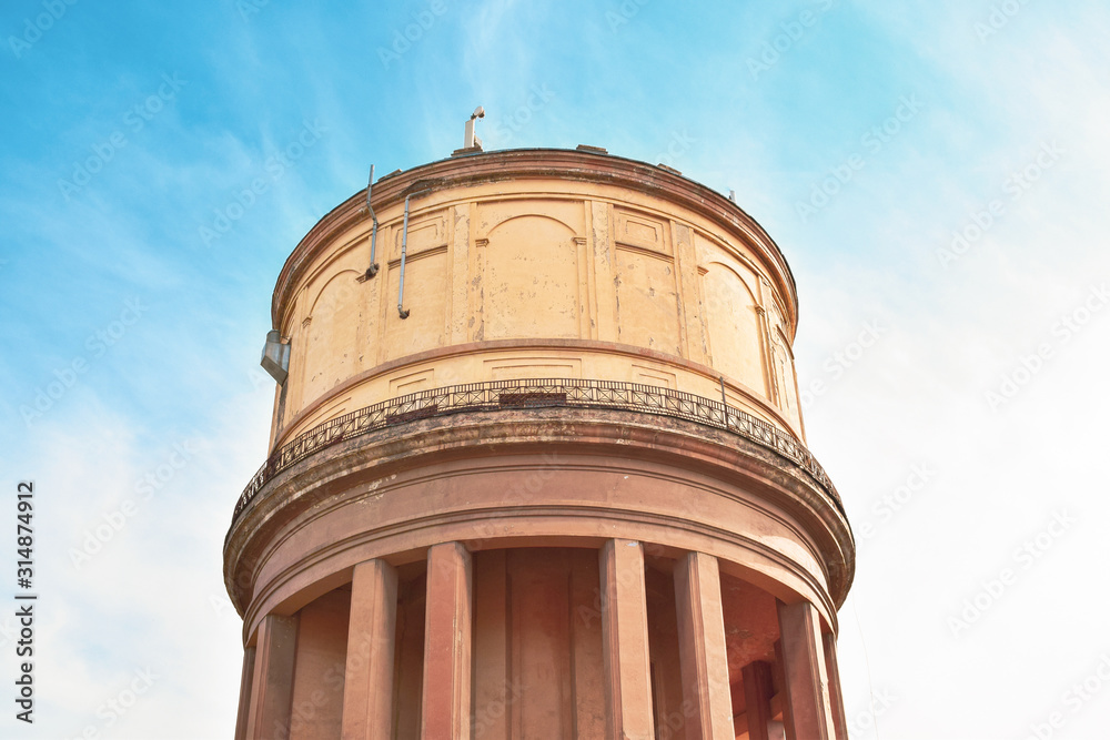 yellow water tower with columns against a blue sky yellow water tower with columns against a blue sky