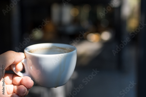Coffee Cup on hand Cafe shop Interior with Blur background