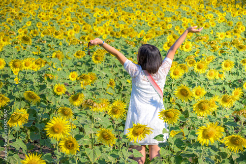 A happy, beautiful young girl standing in a large field of sunflowers, Summer time