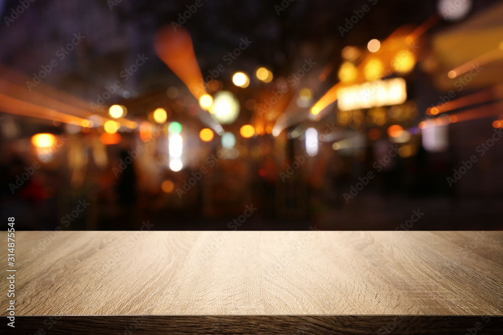 background Image of wooden table in front of abstract blurred restaurant lights