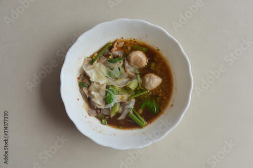 Thai Noodle With Stewed Soup (Kuay Tiew Ruer) served with Pork Ball and Pork. This is one of popular street food menu in Thailand.  photo