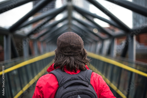 Back of tourist girl with backpack travels through city, against the background of urban bridge yellow lines symmetry explorer hike travel © Valentin