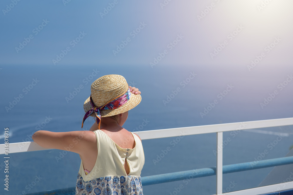 Φωτογραφία European woman in sunhat is standing on the windy seacoast against the marvelous sea view