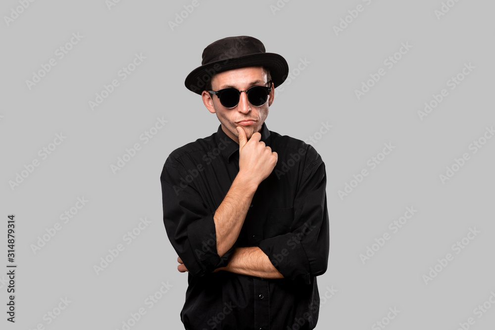 Stylish handsome man a black shirt and pork pie hat isolated over grey background