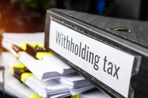 Pile of Taxation document files concept : Withholding tax, retention tax is income tax to paid to government by payer rather than by recipient, applies to employment income, recipient's tax liability