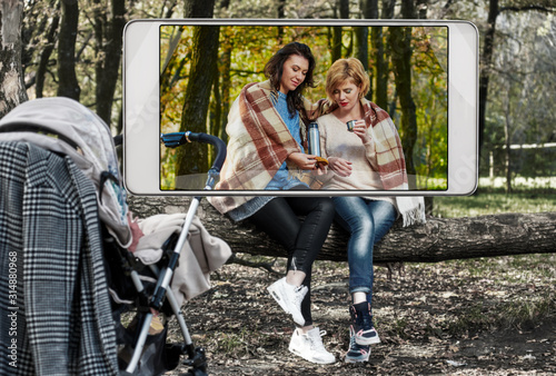 Two women drinking tea in autumn forest  demonstration of device capabilities