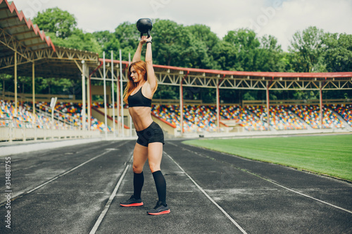 Sports girl at the stadium. Beautiful girl doing sports. The girl raises the weight