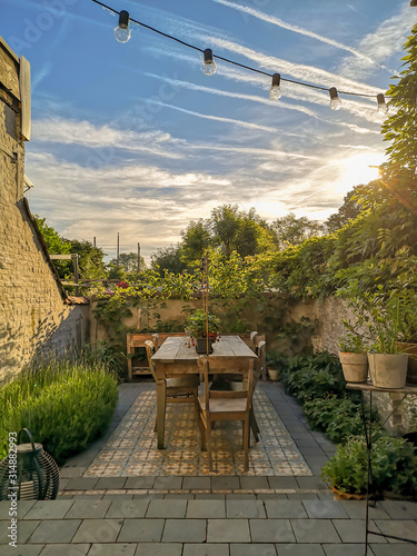 Foto Vintage cement tiles in a small walled urban garden full with green plants and w