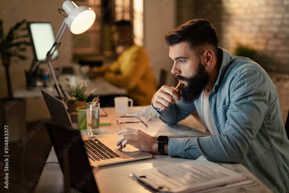 Young businessman working late on laptop in the office. Young businessman working late on laptop in the office.