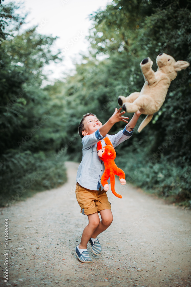 Obraz premium Cute little boy playing with his toy friends in nature. Raising healthy children