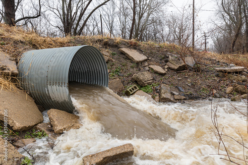 Canvastavla Closeup motion blur of storm water runoff flowing through metal drainage culvert under road