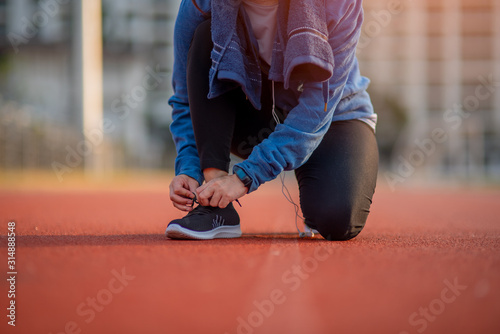 Beautiful female athletes tie shoelaces on sneakers. Beautiful female athletes are sitting on a shoelace on a black sneakers. Healthy lifestyle concepts