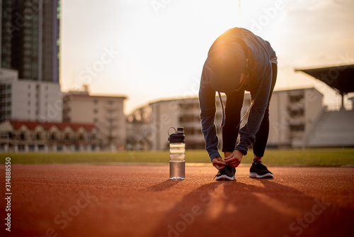 Beautiful female athletes tie shoelaces on sneakers. Beautiful female athletes are sitting on a shoelace on a black sneakers. Healthy lifestyle concepts