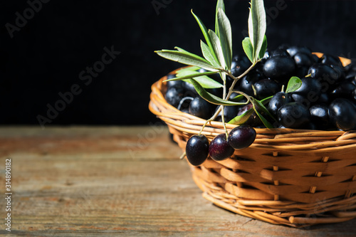 A wiker basket full with ripe fresh black olives from Puglia, Italy, low key photo