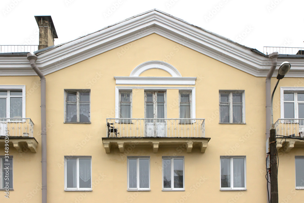 wide balcony of the old yellow building. Triangular roof, white frames, minimalism wide balcony of the old yellow building. Triangular roof, white frames, minimalism