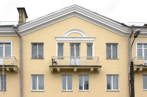 wide balcony of the old yellow building. Triangular roof  white frames  minimalism