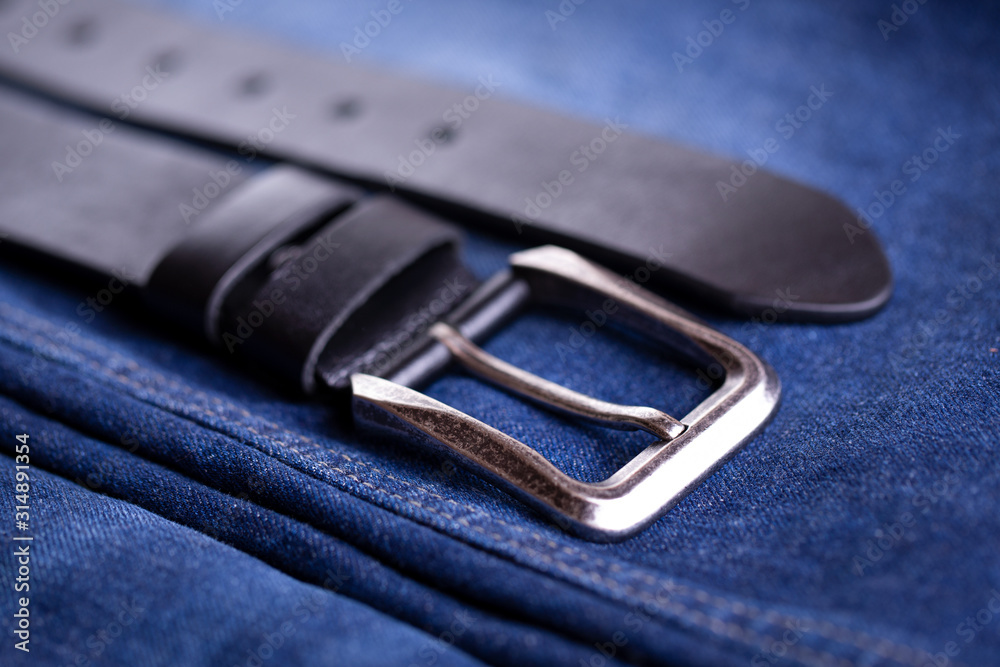 Leather belt lies on denim. Belt accessory wardrobe. Beautiful wide belt and jeans close-up. Leather belt lies on denim. Belt accessory wardrobe. Beautiful wide belt and jeans close-up.