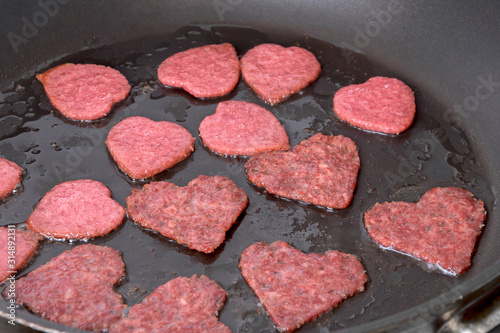 Sausages chorizo salami in the shape of a heart fried ​​in the pan. Homemade food idea for Valentine's Day and Mother's Day