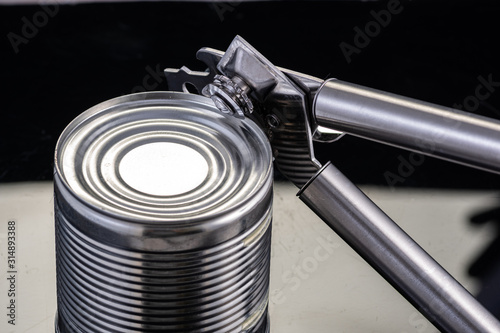 a handmade can opener from Finland next to a can on a black background