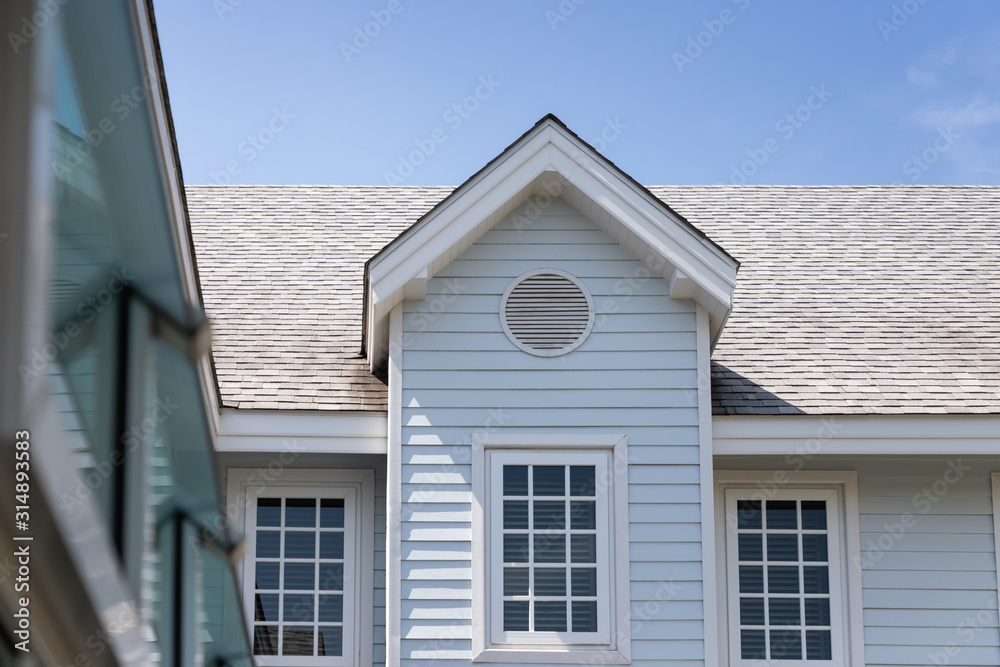 wooden house with roof shingle tiles against blue sky.