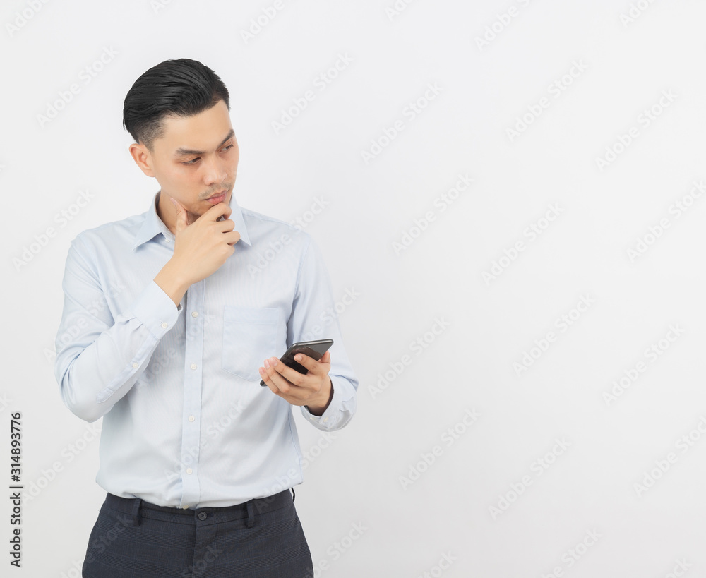 Young handsome asian business man playing smartphone and thinking isolated on white background. Young handsome asian business man playing smartphone and thinking isolated on white background.