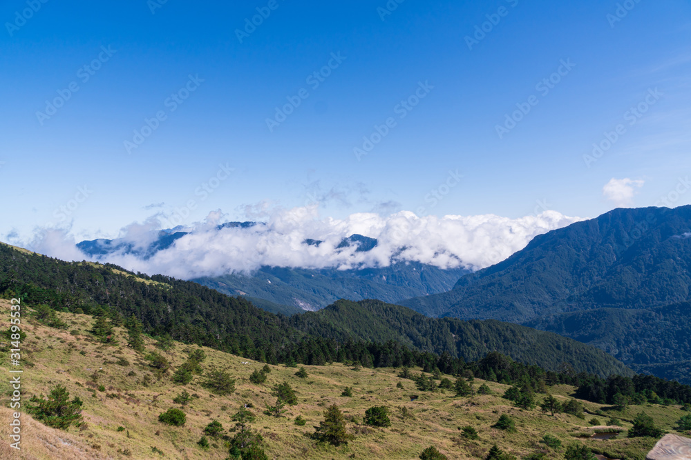 Mountains and Hills panoramia View with many stacked foggy , smoky ranges and meadow.