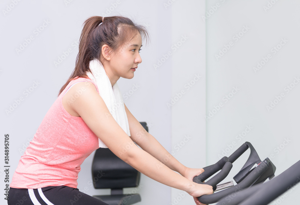 Fit asian young woman using exercise bike at the gym. Fit asian young woman using exercise bike at the gym.