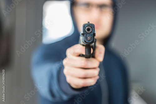 Crime or robbery concept: Man with black gun is aiming with his weapon