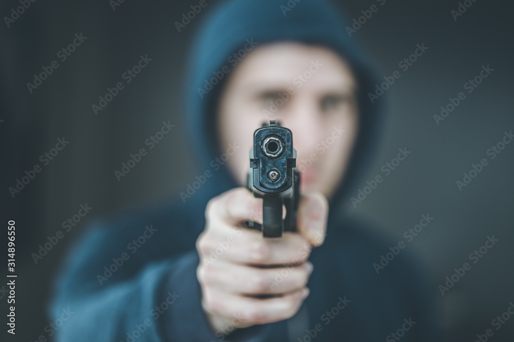 Crime or robbery concept: Man with black gun is aiming with his weapon Crime or robbery concept: Man with black gun is aiming with his weapon