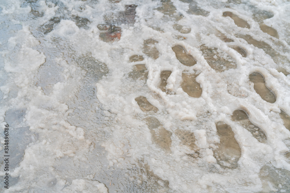 Traces of shoes in slush. The sidewalk is covered with melted snow. Traces of shoes in slush. The sidewalk is covered with melted snow.