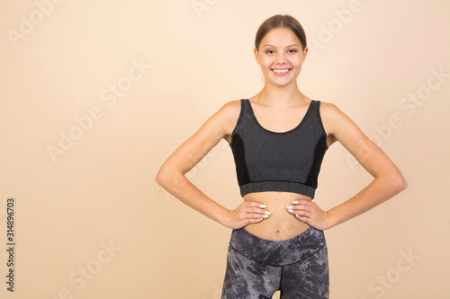 beautiful young woman in sportswear on a beige background