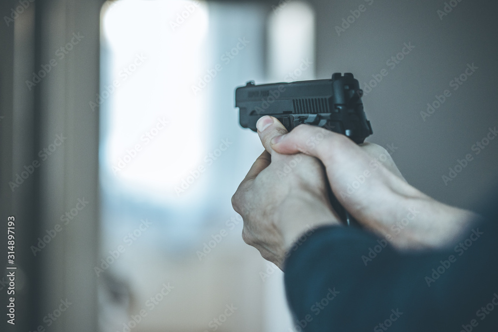 Crime or robbery concept: Man with black gun is aiming with his weapon Crime or robbery concept: Man with black gun is aiming with his weapon