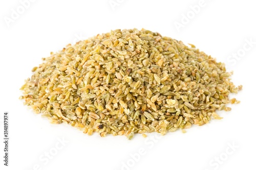 Heap of uncooked, raw freekeh or firik, roasted wheat grain over white photo