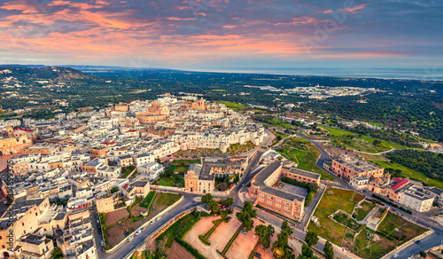 View from flying drone. Unbelievable spring sunrise in Ostuni town. Fantastic morning cityscape of Apulia, Italy, Europe. Traveling concept background.