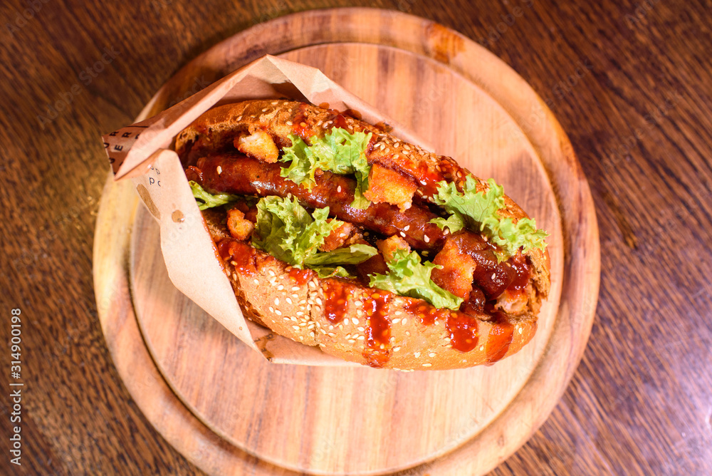 Big tasty hot dog on a wooden tray on the table. Unhealthy food. Big tasty hot dog on a wooden tray on the table. Unhealthy food.