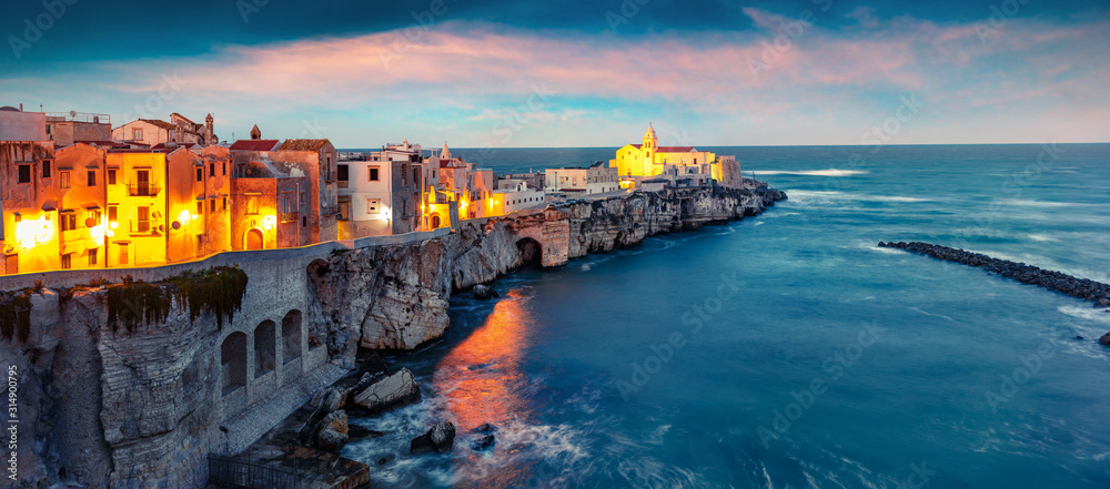 Dramatic evening cityscape of Vieste - coastal town in Gargano National Park, Italy, Europe. Splendid spring sunset on Adriatic sea. Traveling concept background.