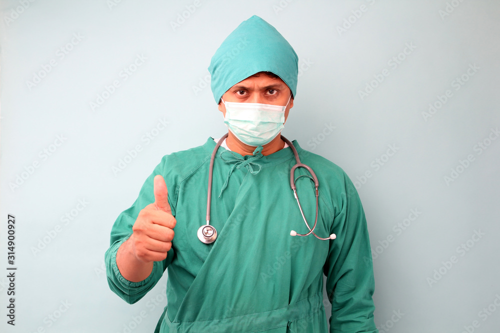 male asia surgeon,surgeon showing stethoscope wearing surgeon mask, on a blue background in studio. male asia surgeon,surgeon showing stethoscope wearing surgeon mask, on a blue background in studio.