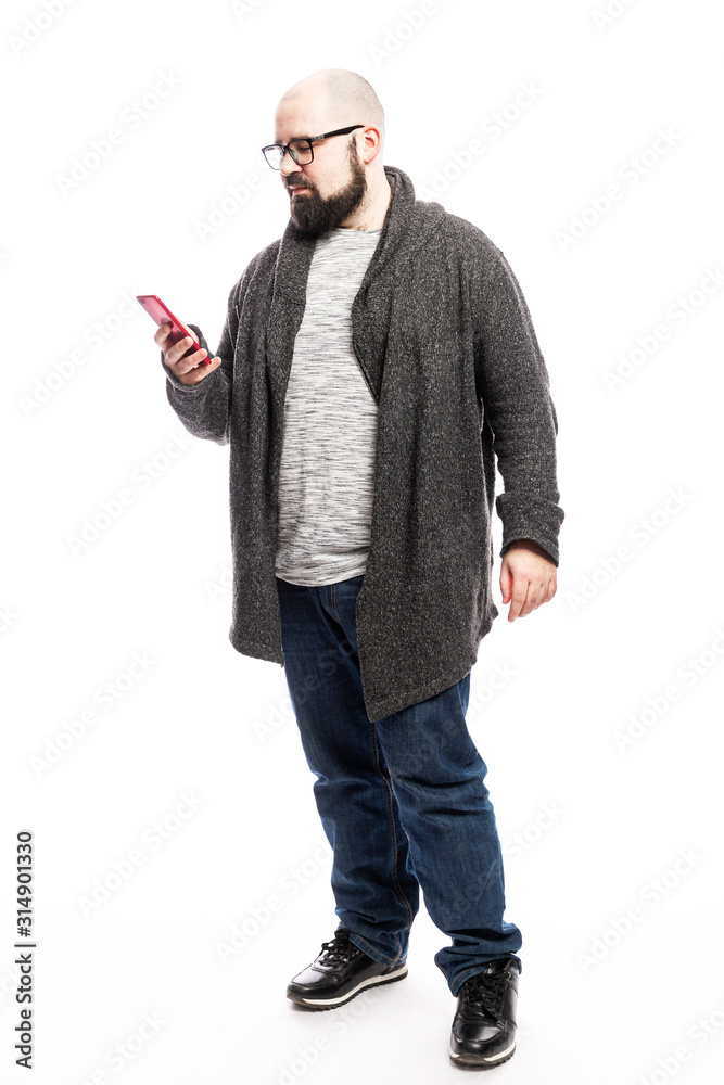 Fototapeta premium Bald man in glasses with a phone in his hands. Full height. Isolated over white background. Vertical.