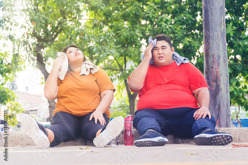 Fototapeta Naklejka Na Ścianę i Meble -  Fat Asian couple wiping their sweats after workout