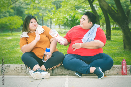 Fat Asian man offering water to his female friend