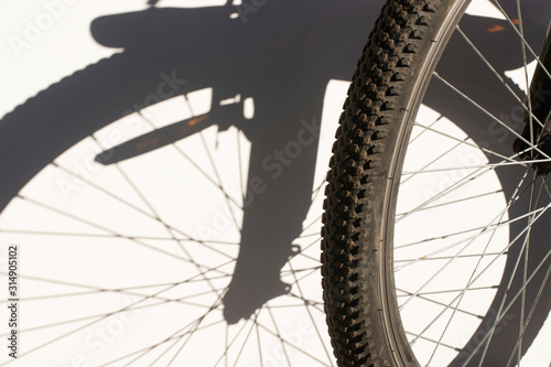 Bicycle wheel and gray shadow from the wheel on a white wall.