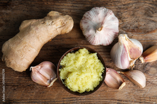 Fresh garlic and ginger on wooden table, flat lay. Natural cold remedies photo