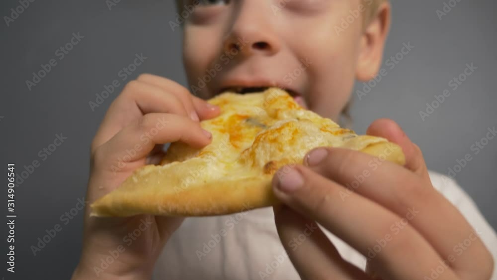 The boy is eating pizza. Unhealthy diet. Fast food home The boy is eating pizza. Unhealthy diet. Fast food home