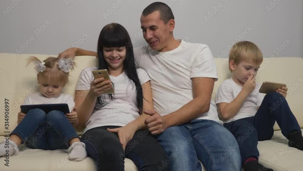 Happy family sitting on the couch, having fun making purchases in the online store.Working together, mom dad and kids enjoy modern technology at home. Happy family sitting on the couch, having fun making purchases in the online store.Working together, mom dad and kids enjoy modern technology at home.