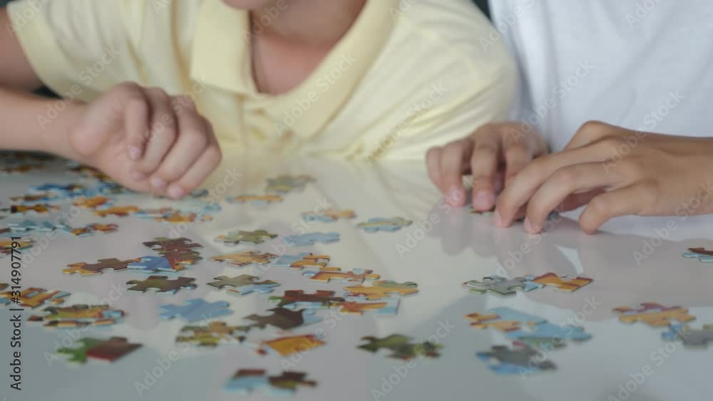 Two boys collect puzzles. Teamwork. Way to success. Happy family is engaged in self-development Two boys collect puzzles. Teamwork. Way to success. Happy family is engaged in self-development