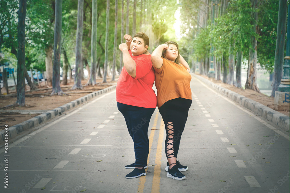 Fat couple posing by raising their arm muscles