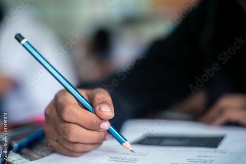 Hand of Student doing test or exam in classroom of school with stress