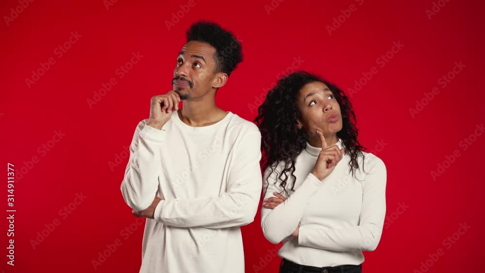 Portrait of young thinking pondering couple on red studio background. Man and woman look in different directions and everyone thinks about his problem. Portrait of young thinking pondering couple on red studio background. Man and woman look in different directions and everyone thinks about his problem.